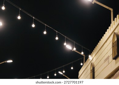 Multiple strands of small, glowing light bulbs are suspended across the frame, providing illumination and a decorative feel.