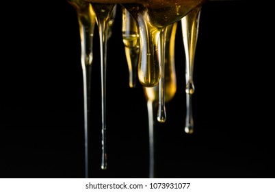 Multiple Strings of Honey Drip in front of dark background