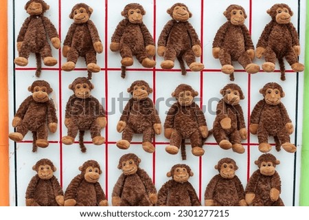 Multiple stuffed toy monkeys are attached to a whiteboard and divided by red lines. The animals have soft brown material with beige colored feet and hands. There are two rows of fluffy cuddly dolls. 