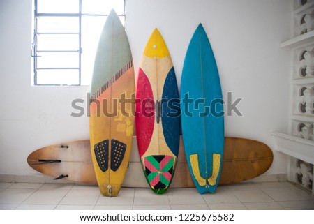 Multiple surfboards staying by the wall inside of the house with the white walls. Tropical lifestyle. Downshifting concept. 