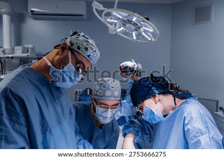 Multiple surgeons performing operation in fully equipped hospital operating room. Surgery concept.
