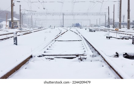 Multiple train tracks during snowfall quickly covered with fluffy white snow on a winter day. Copy space.