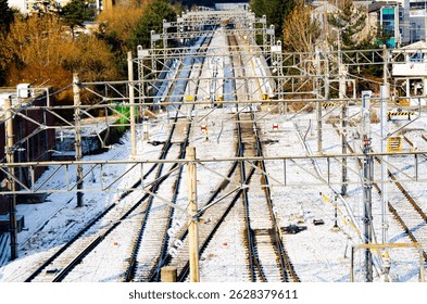 Multiple train tracks during snowfall quickly covered with fluffy white snow on a winter day. Copy space.