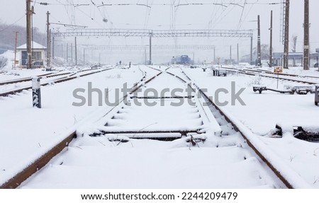 Multiple train tracks during snowfall quickly covered with fluffy white snow on a winter day. Copy space.