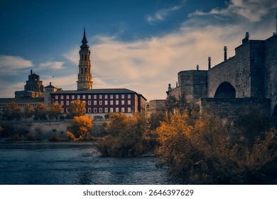 Multiple view of part of the old town of Zaragoza from the opposite bank of the Ebro River, with the archbishop's palace in front and the stone bridge to the right.
                            