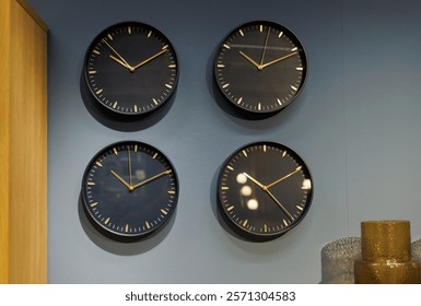 Multiple wall clocks displaying different times on a gray wall in a modern room