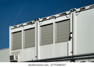 Multiple white construction containers with rolled-down shutters at a large site in Cologne. Symbol for the building sector.