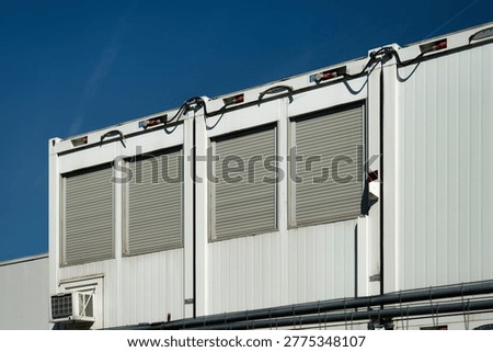 Multiple white construction containers with rolled-down shutters at a large site in Cologne. Symbol for the building sector.