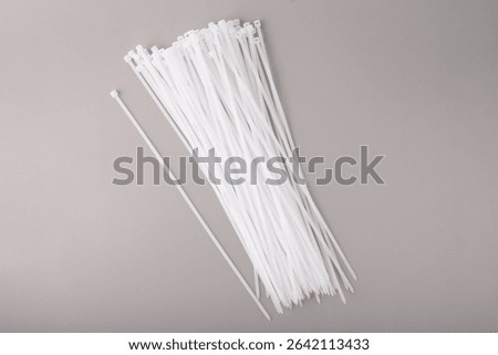 Multiple white nylon cable ties in plastic bags for organizing and fastening wires. Ideal for hardware stores, electrical suppliers, and DIY product catalogs.