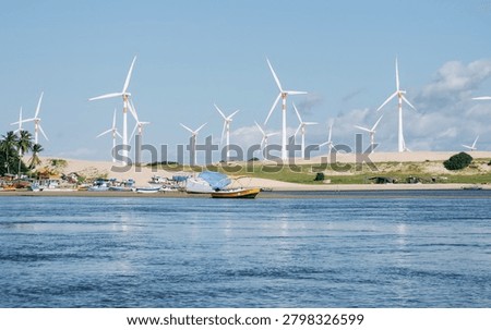Multiple Wind Turbines Over Dunes with Anchored Boats and River in Northeast Brazil