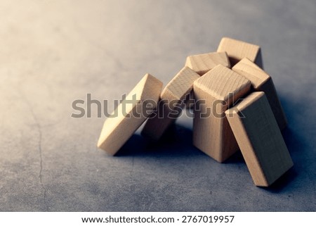 Multiple wood blocks rely on a single support, representing overdependence, key person risk, and vulnerability in business structure or operations