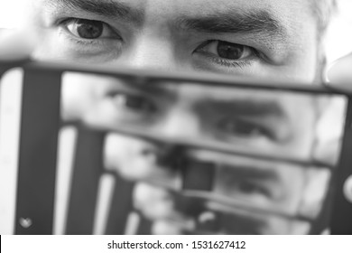 Multiplying Effect Between Two Mirror Surfaces. Re-reflection Of A Male Face In Perspective. Image In Screen Of Mobile Cell Phone. Man Portrait.