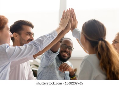 Multiracial associate business people group teammates hands give high five together promising unity as dream team concept, corporate success, teambuilding and loyalty, support in teamwork, coaching