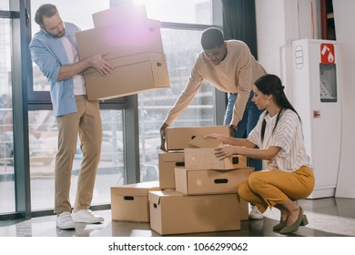 multiracial business colleagues carrying cardboard boxes during relocation in new office  - Powered by Shutterstock