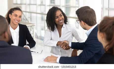Multiracial businessman businesswoman shake hands starting collaboration at group negotiations, positive people gathered at modern office boardroom, partnership teamwork and business etiquette concept