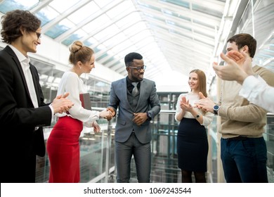 multiracial businessmen making agreement, their colleague standing near by