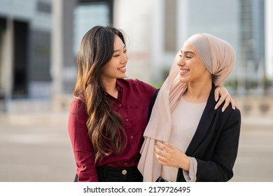 multiracial businesswomen friends hug outside, asian woman with muslim woman in buildings. - Shutterstock ID 2179726495