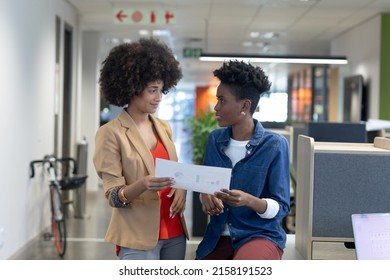 Multiracial businesswomen looking at each other while discussing over document at workplace. unaltered, business, teamwork and modern office concept. - Shutterstock ID 2158191523