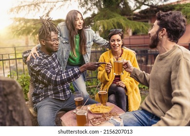 Multiracial Cheerful Group Of Young People Having A Party Together Sitting, Drinking, Toasting Beers And Enjoying Time Together At The Countryside Pub Brewery In The Afternoon Weekend