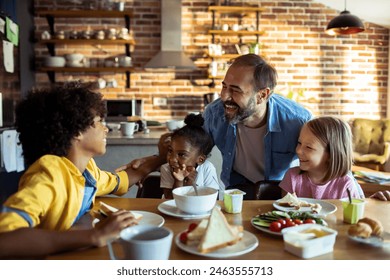 Multiracial children sharing a joyful moment with father at kitchen table - Powered by Shutterstock