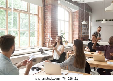 Multiracial Corporate Team Launching Paper Planes In Coworking Office Interior, Diverse Employees Group Laughing Having Fun At Work, Lazy Workers Wasting Time, Startup Concept, Career Dreams Hopes