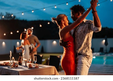 Multiracial couple, Caucasian girl and African-American young man, happy and in love while dancing at a poolside party - Powered by Shutterstock