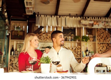 Multiracial Couple Paying Bill At Restaurant.