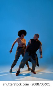 Multiracial Dance Couple Dancing Hip Hop Dance. Concept Of Contemporary Dancing. Idea Of Choreography. Flexible European Man And Black Woman. Blue Background In Studio With Shadow On Floor. Copy Space