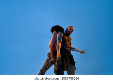 Multiracial Dance Couple Dancing Hip Hop Dance. Concept Of Contemporary Dancing. Idea Of Choreography. Caucasian Man And Black Woman Standing Back To Back On Blue Background In Studio. Copy Space