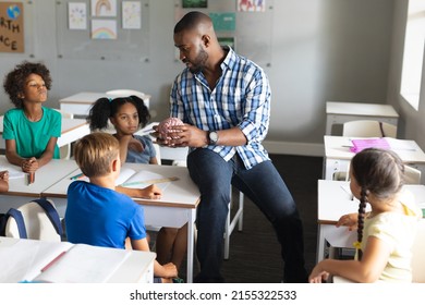 Multiracial elementary students looking at multiracial young male teacher explaining brain model. unaltered, education, childhood, teaching, science, stem and school concept. - Powered by Shutterstock