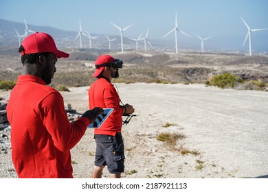 Multiracial engineer men using virtual reality headset on a windmill farm - Focus on african man face