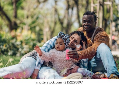 Multiracial Family Concept. Black Father And White Mother Playing With Their Daughter In The Park And Spending The Day Together.