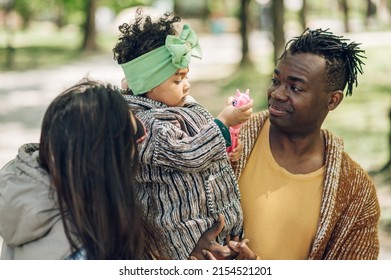 Multiracial Family Concept. Black Father And White Mother Playing With Their Daughter In The Park And Spending The Day Together.