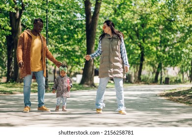 Multiracial Family Concept. Black Father And White Mother Playing With Their Daughter In The Park And Spending The Day Together.