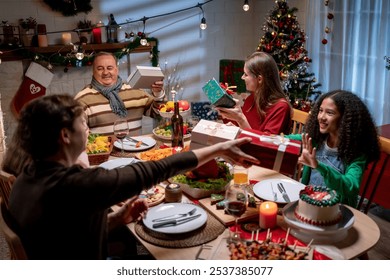 Multiracial family exchanging presents during Christmas party at home. Lovely family members receive gift from relatives while having dinner celebrate holiday Thanksgiving xmas on dining table at home - Powered by Shutterstock