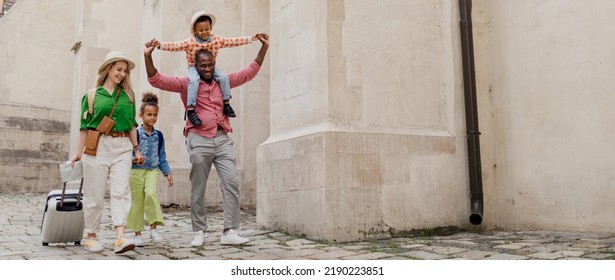 Multiracial Family Travel Together With Suitcases, Walking In Old City Centre.