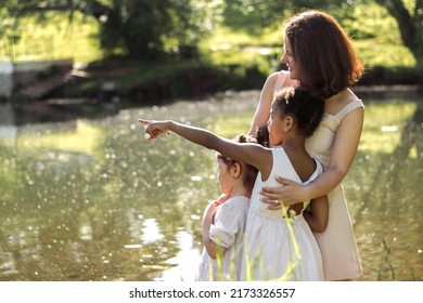 A Multiracial Family Watching Birds On A Pond On A Summer Day In The Park,side View.Summer,diversity Concept.Selective Focus,copy Space.