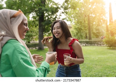 Multiracial Female Friends Eat Pizza And Smile In The Park, Focus On Asian Woman.