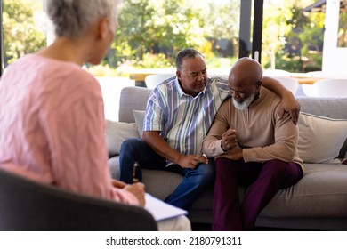 Multiracial female therapist looking at senior man consoling male friend crying in retirement home. Sad, together, comfort, unaltered, stress, support, assisted living, group therapy, psychotherapy. - Powered by Shutterstock