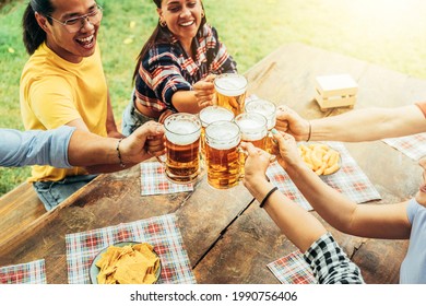 Multiracial Friends Celebrating Toasting Beer Pint At Park Outdoor - Young People Having Fun Cheering Glasses Together At Brewery Pub Garden - Friendship, Youth And Beverage Concept