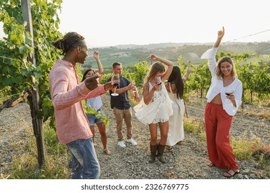 Multiracial friends dancing at summer party inside vineyards - Happy people having fun together drinking red wine  at coutryside resort - Travel, celebration and tasting event concept - Focus on faces