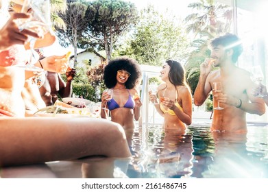 Multiracial friends drinking champagne together on pool party - Diverse young people having fun at a holiday resort - Summer vacations concept with guys and girls hanging outside together - Powered by Shutterstock