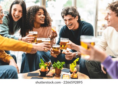 Multiracial friends drinking and toasting beer at brewery bar pub-Happy diverse people cheering glasses and having fun enjoying happy hour celebrating party-Beverage life style concept with guys - Shutterstock ID 2266592895