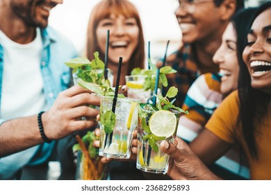 Multiracial friends enjoying happy hour toasting fresh mojito cocktails at open bar - Happy group of young people celebrating summer party together - Life style food and beverage concept - Powered by Shutterstock