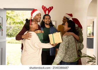 multiracial friends exchanging gifts and hugging at home during festive Christmas celebration. Holidays, friendship, togetherness, tradition, warmth, giving - Powered by Shutterstock