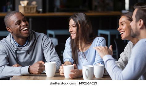 Multiracial friends girls and guys having fun laughing drinking coffee tea in coffeehouse, happy diverse young people talking joking sitting together at cafe table, multicultural friendship concept - Shutterstock ID 1492614623