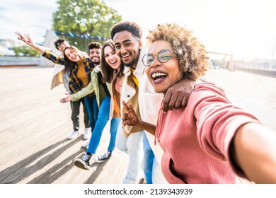 Multiracial friends group taking selfie pic with smartphone outside - Happy young people having fun walking on city street - Friendship concept with guys and girls enjoying summertime day outside - Powered by Shutterstock