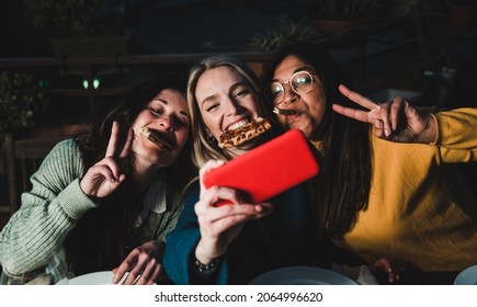 Multiracial friends having fun doing selfie with mobile phone at pizza bar restaurant outdoor - Soft focus on center girl face - Powered by Shutterstock