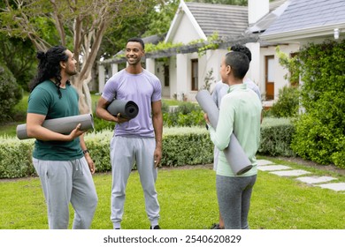 multiracial friends holding yoga mats chatting happily in garden before outdoor workout. Friendship, wellness, exercise, socializing, fitness, healthy lifestyle - Powered by Shutterstock