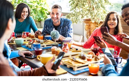 Multiracial friends interacting with mobile phone at coffee bar - People having fun at cafeteria on morning brunch time - Life style concept with happy men and women at cafe venue - Bright filter 